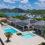 Aerial view of a luxury villa with two pools, palm trees, and solar panels on the roof." (Note: ensure this alt text is concise and without stray quotes)