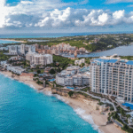 Aerial view of a tropical coastline with high-rise hotels along a sandy beach and turquoise sea.