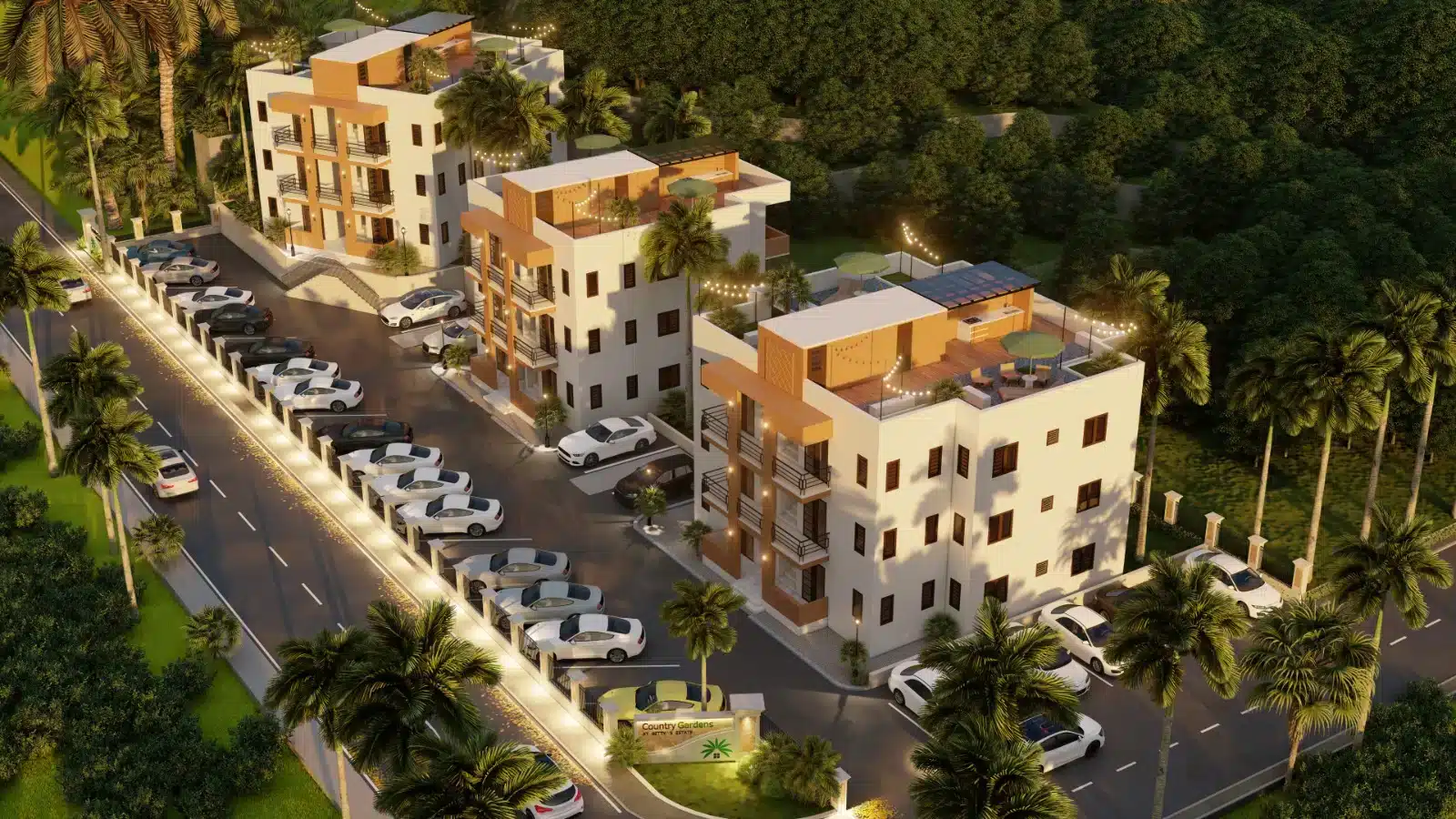 Aerial view of a modern white apartment complex with orange accents, multiple rooftop terraces, string lights, and a lined parking lot surrounded by palm trees and greenery at dusk.